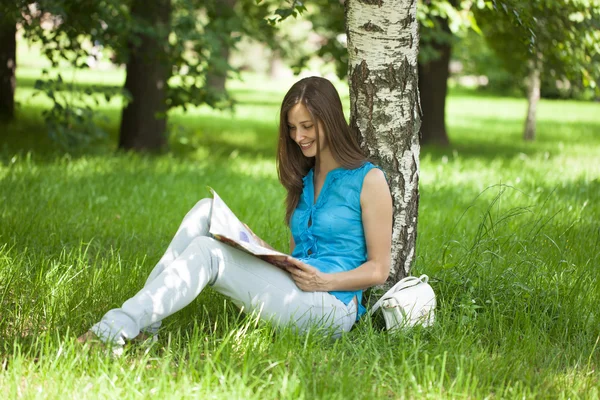 Mulher feliz folheando através de uma revista enquanto sentado no summ — Fotografia de Stock