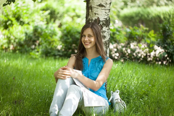 Gelukkige vrouw die bladeren door een tijdschrift zittend in de summ — Stockfoto