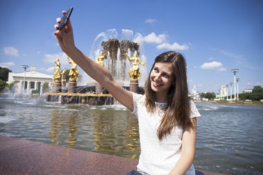 Gülümseyen kadın almak bir fotoğrafını bir akıllı telefon ile. Selfi