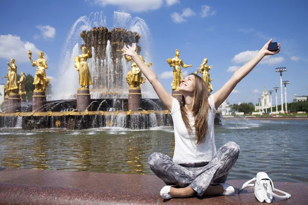 Ung vacker kvinna har en vila som sitter nära fontänen — Stockfoto
