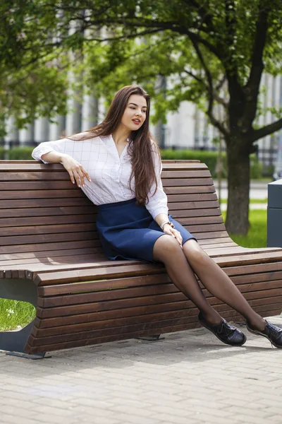 Junges schönes Mädchen sitzt auf einer Bank im Sommerpark — Stockfoto