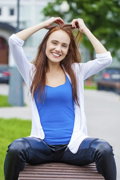 Jeune belle fille assise sur un banc dans le parc d'été — Photo