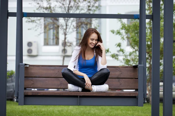 Ung vacker flicka satt på en bänk i parken sommaren — Stockfoto