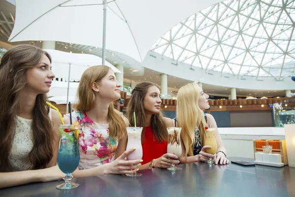 Cerca de cuatro mujeres jóvenes atractivas que beben cócteles en la tienda — Foto de Stock
