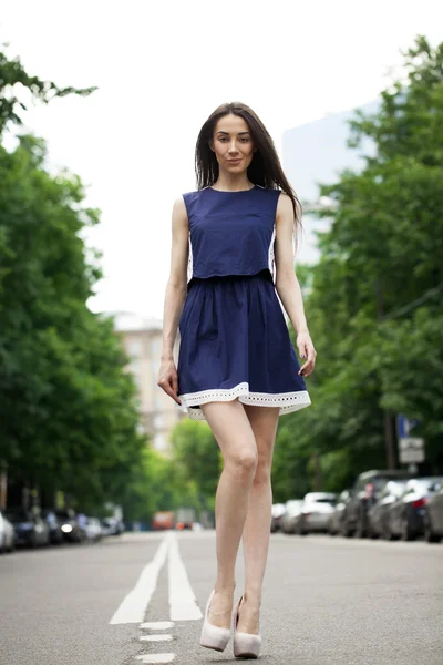 Young beautiful woman in a blue short dress walking on the road — Stock Photo, Image