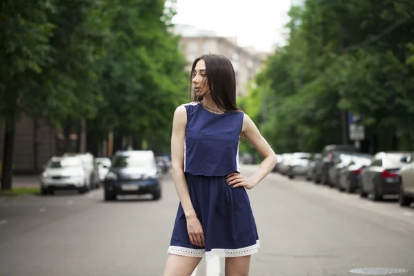 Jovem mulher bonita em um vestido curto azul andando na estrada — Fotografia de Stock