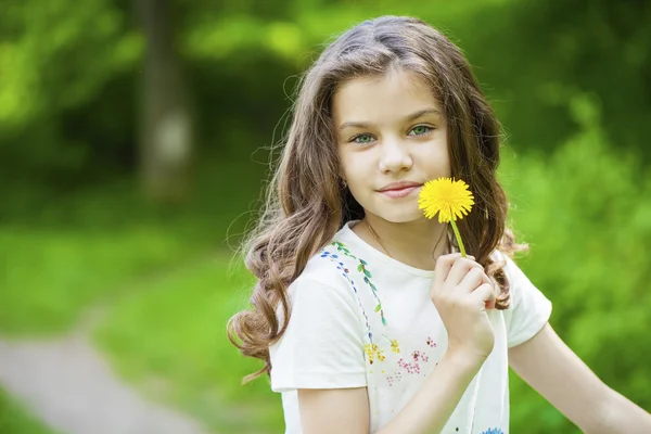 Mała dziewczynka wącha żółty mniszek lekarski — Zdjęcie stockowe