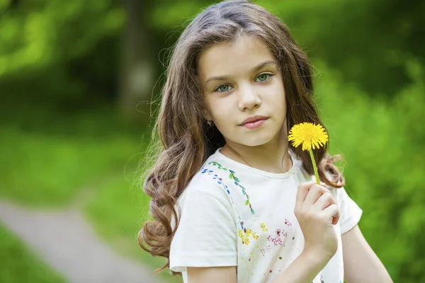 Little girl smelling a yellow dandelion — Stock Photo, Image