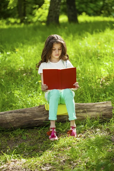 Orman ağaç kütüğü üzerinde oturup kitap ile sevimli küçük kız