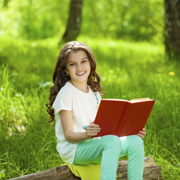 Charming little girl in forest with book sitting on tree stump — Stock Photo, Image