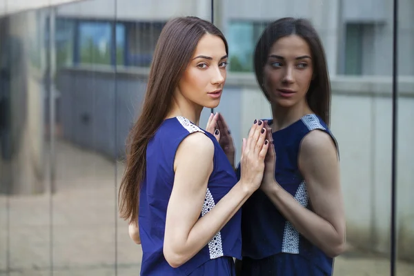 Senhora elegante em vestido azul posando perto de parede espelhada — Fotografia de Stock