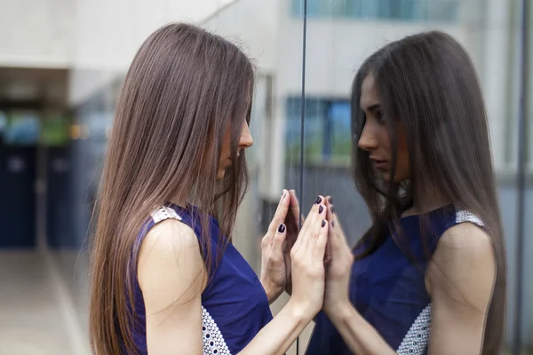 Snygg kvinna i blå klänning poserar nära spegelvägg — Stockfoto