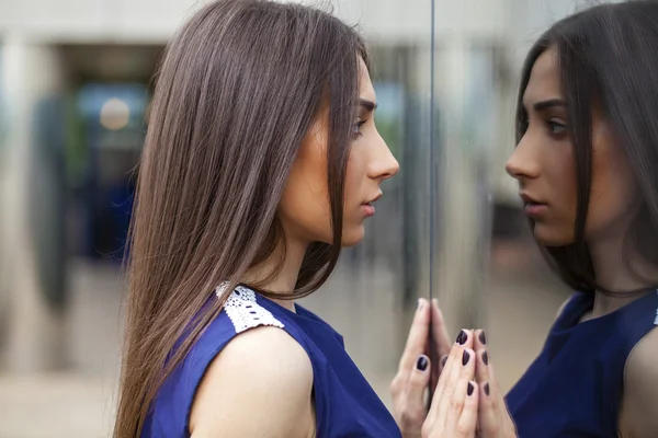 Elegante dama en vestido azul posando cerca de la pared espejada — Foto de Stock