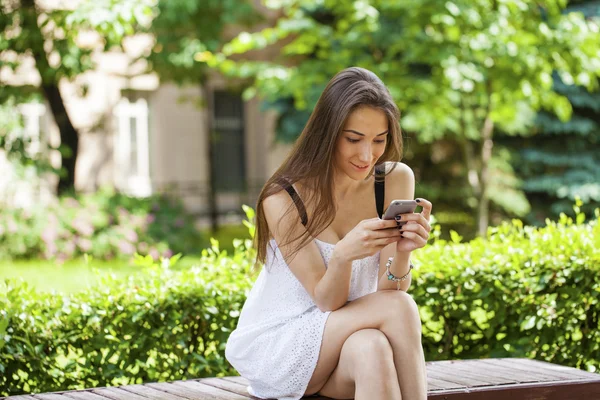 Jeune femme brune lisant un message au téléphone — Photo