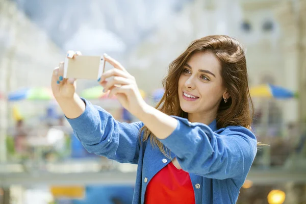 Güzel, gülümseyen kadın bir smartp ile bir fotoğrafını alın — Stok fotoğraf