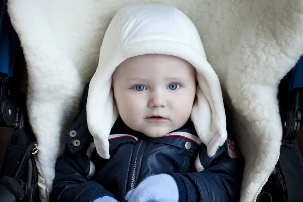 Niño está acostado en un cochecito con ropa de invierno —  Fotos de Stock