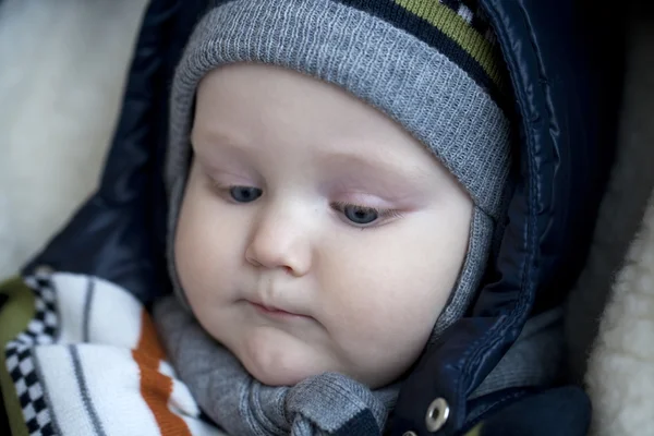 Niño está acostado en un cochecito con ropa de invierno —  Fotos de Stock