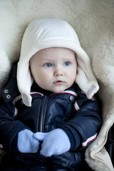 Niño está acostado en un cochecito con ropa de invierno —  Fotos de Stock