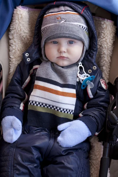 Niño está acostado en un cochecito con ropa de invierno —  Fotos de Stock