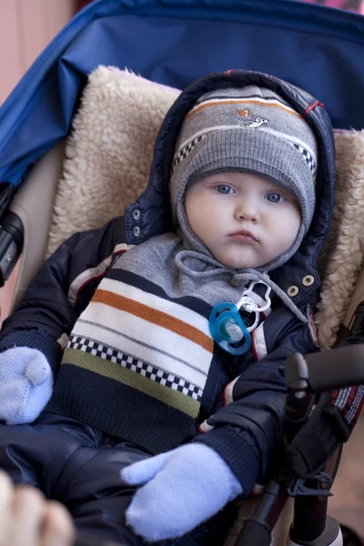 Enfant garçon est couché dans une poussette en vêtements d'hiver — Photo