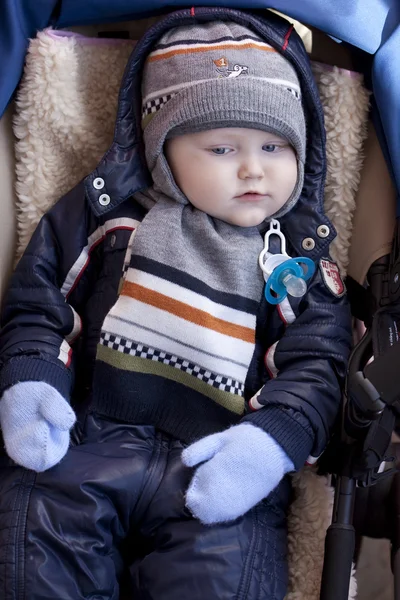 Niño está acostado en un cochecito con ropa de invierno —  Fotos de Stock