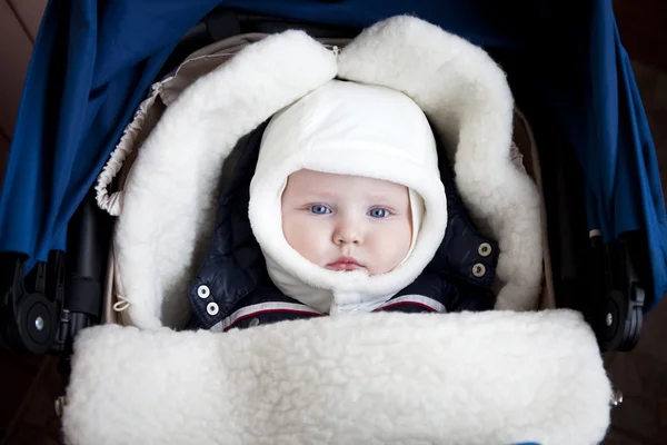 Niño está acostado en un cochecito con ropa de invierno —  Fotos de Stock