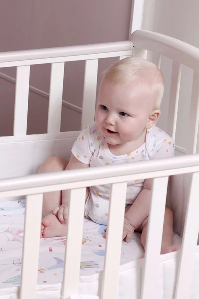 Little boy sitting in a crib — Stock Photo, Image