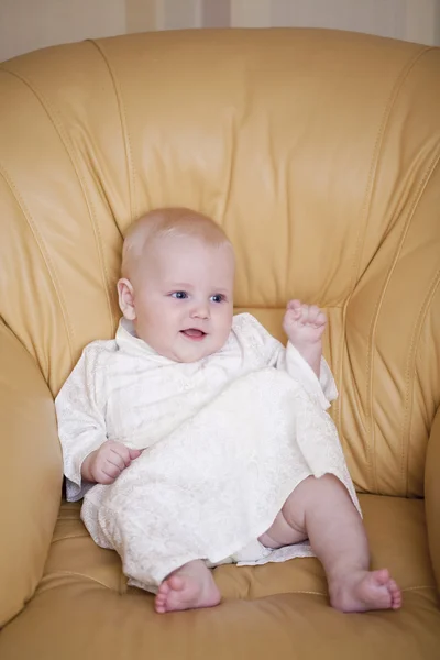 Le petit garçon est assis sur une chaise jaune — Photo