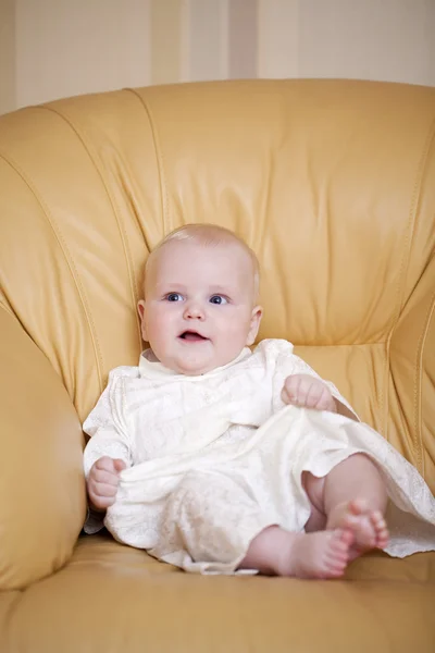 Menino está sentado em uma cadeira amarela — Fotografia de Stock