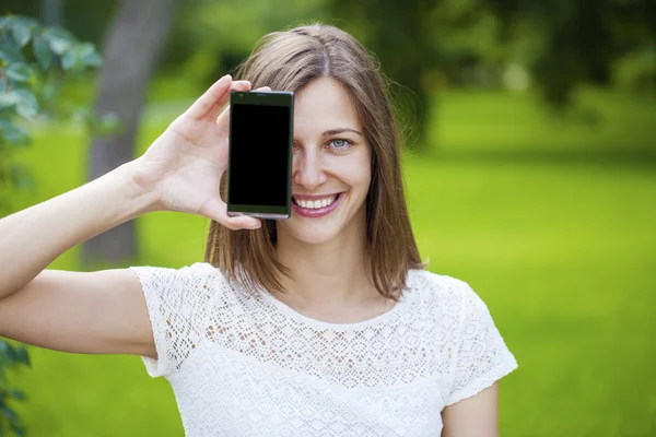 Krásná mladá dívka ukazuje váš smartphone obrazovky — Stock fotografie