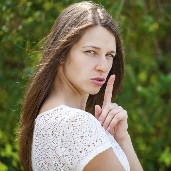 Young beautiful brunette woman has put forefinger to lips as sig — Stock Photo, Image