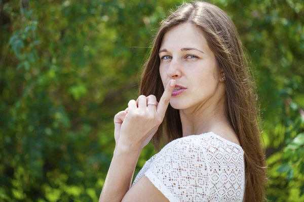 Genç güzel esmer kadın işaret parmağı SIG dudaklarını koydu