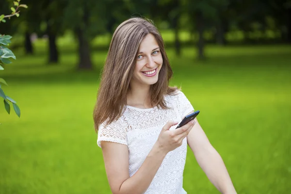 Femme textos sur le téléphone intelligent marche dans le parc d'été — Photo