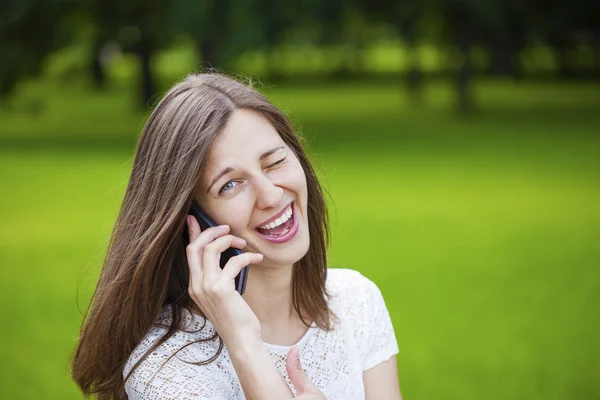 Portrait of beautiful dark haired young woman speaking on mobile — Stock Photo, Image