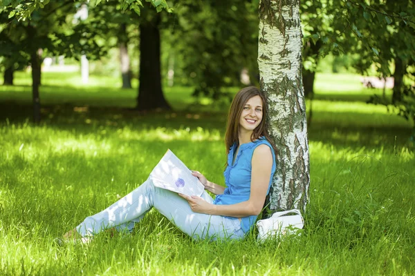 Ung vacker kvinna sitter i parken sommaren — Stockfoto