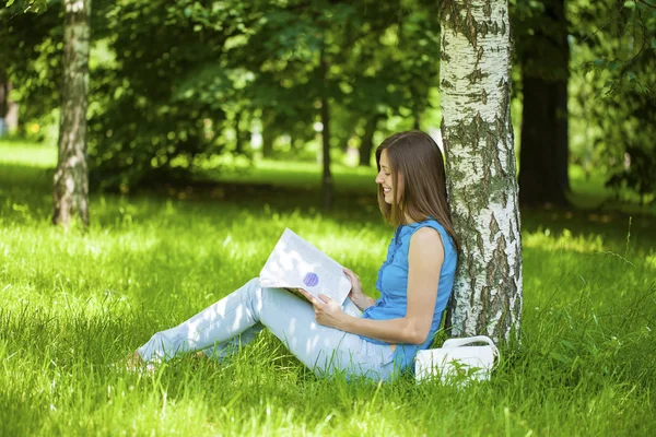 Νεαρή όμορφη γυναίκα που κάθεται στο πάρκο καλοκαίρι — Φωτογραφία Αρχείου