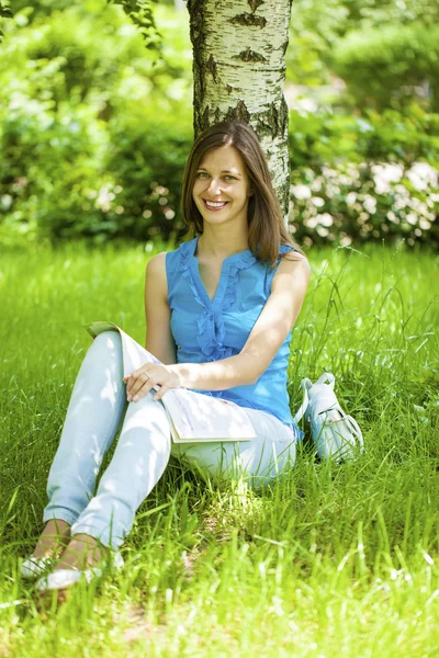 Junge schöne Frau sitzt im Sommerpark — Stockfoto