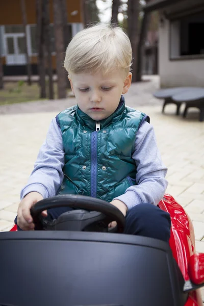 Little boy driving big toy car, spring outdoors — Stock Photo, Image