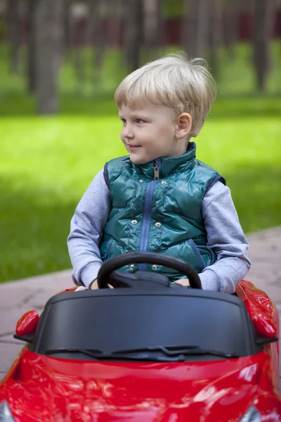 Little boy driving big toy car, spring outdoors — Stock Photo, Image