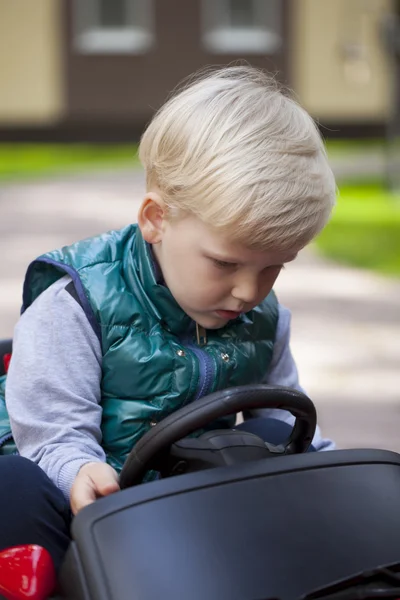 Niño pequeño conduciendo coche de juguete grande, primavera al aire libre —  Fotos de Stock