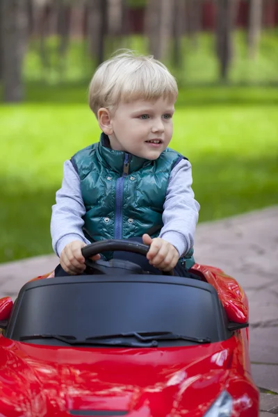 Niño pequeño conduciendo coche de juguete grande, primavera al aire libre —  Fotos de Stock