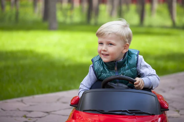 Petit garçon conduisant une grosse voiture jouet, printemps à l'extérieur — Photo