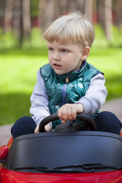 Little boy driving big toy car, spring outdoors — Stock Photo, Image