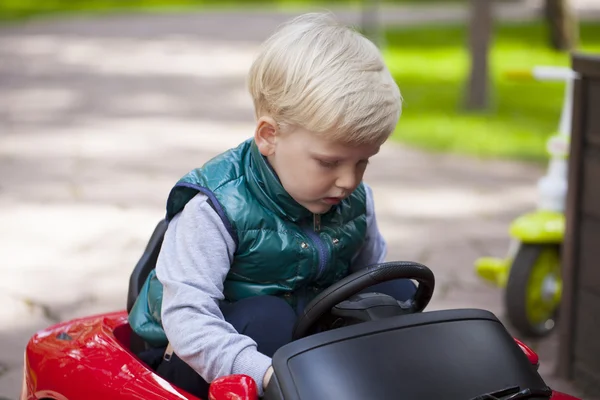 Niño pequeño conduciendo coche de juguete grande, primavera al aire libre —  Fotos de Stock