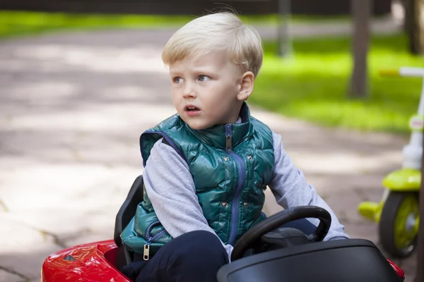 Маленький хлопчик за кермом великої іграшкової машини, весна на відкритому повітрі — стокове фото