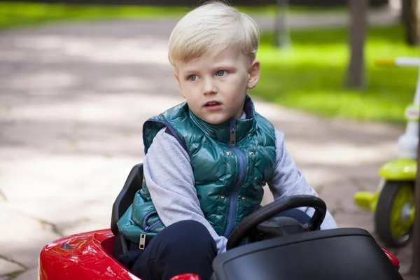 Liten pojke drivande stor leksaksbil, våren utomhus — Stockfoto