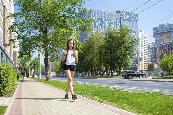 Unga vackra kvinnan i svart kort gå på sommaren stree — Stockfoto