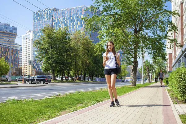 Unga vackra kvinnan i svart kort gå på sommaren stree — Stockfoto