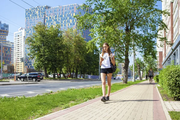 Unga vackra kvinnan i svart kort gå på sommaren stree — Stockfoto