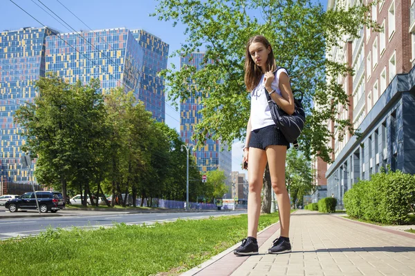 Unga vackra kvinnan i svart kort gå på sommaren stree — Stockfoto